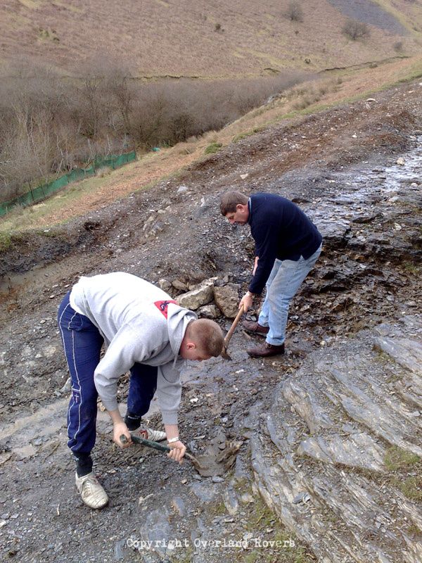 2 men with shovels digging on a rocky path