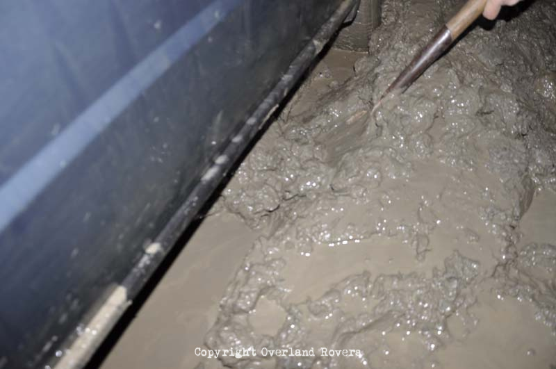 A shovel digging out saturated mud from under the side of a car