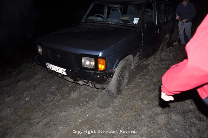 A blue Land Rover Discovery 1, at night, in deep saturated mud