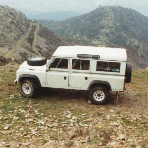White Land Rover 110 high in the Pyrenees, with a sweeping vista in the background